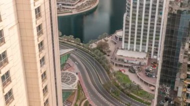 Dubai çoklu emtia merkezi karma kullanım bölgesinin bir parçası olan JLT bölgesi hava zaman diliminde uzun konut binaları. Kuleler arasındaki göl kenarındaki yolda trafik vardı.