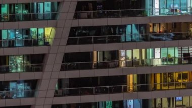 Apartman binasının parlayan pencerelerinin gece görüşü. Işıklı ve hareketli yüksek gökdelenler