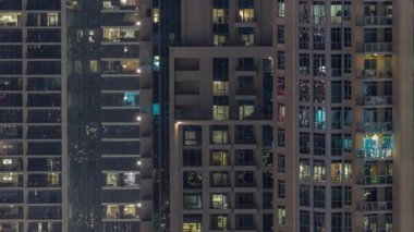 Modern konut binalarındaki büyük parlayan pencereler gece saatlerinde, sıra sıra parlıyor..