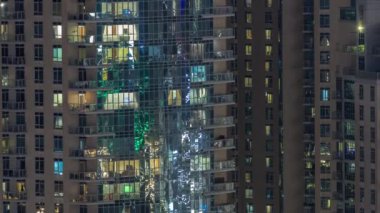 Modern apartmanlardaki büyük parlayan pencereler gece saatlerinde zaman ayarlı, sıralı pencereler ışık saçıyor.