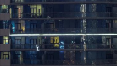 Modern ofisteki büyük parlayan pencereler ve konut binaları geceleri zaman ayarlı, sıralı pencereler ışık saçıyor.