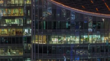 Modern ofisteki büyük parlayan pencereler ve konut binaları gece saatlerine göre ayarlanıyor, pencereler ışık saçıyor. Finans bölgesinde gökdelenler