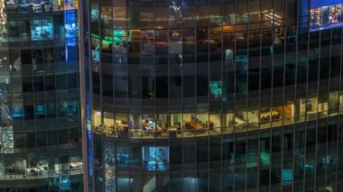 Modern ofisteki büyük parlayan pencereler ve konut binaları gece saatlerine göre ayarlanıyor, pencereler ışık saçıyor. Finans bölgesinde gökdelenler