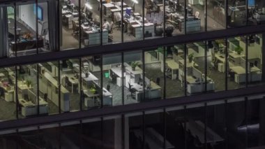 Modern ofis binalarındaki büyük parlayan pencereler geceleri zaman ayarlı, sıra sıra parlıyor. Açık alan çalışma yerleri
