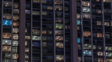 Modern ofisteki büyük parlayan pencereler ve konut binaları gece saatlerine göre ayarlanıyor, pencereler ışık saçıyor. Birçok apartman bloğu