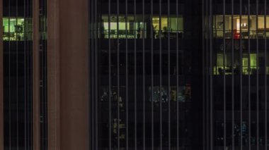 Modern ofis binalarındaki pencere ışıkları geceleri zaman ayarlı. Çok katlı gökdelenlerin içinde açık uzay odaları var. Masalarda çalışan insanlar