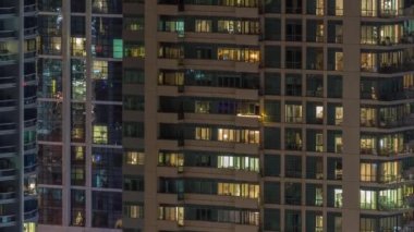 Modern ofisteki birçok pencere ışığı ve konut binaları geceleri zaman ayarlı. İçinde aydınlık odalar olan çok katlı gökdelenler.