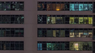 Modern apartmanlardaki pencere ışıkları geceleri zaman ayarlı. İçinde aydınlık odalar olan çok katlı gökdelenler.