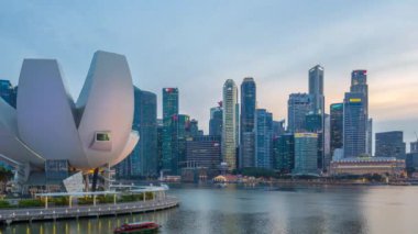 Futuristic architecture flower shape design of the Art Science museum day to night transition timelapse after sunset. Skyscrapers skyline city of Singapore.