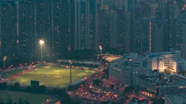 Fei ngo shan Kowloon Tepesinden gece gündüz geçiş zamanı Hong Kong şehir manzarası silueti. Yüksek binalar ve futbol sahası.