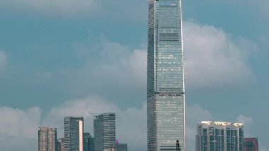 Hong Kong iş merkezi gökdelenleri günden geceye geçiş zamanı bulutlu mavi bir gökyüzü ile, gün batımından sonra Hong Kong adasının batı noktasından yansıması ile