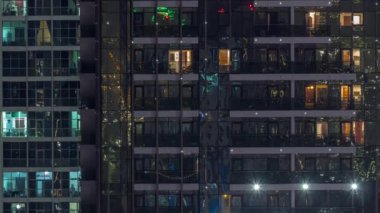 Dışarıdaki apartmanın gece manzarası renkli zaman çizelgesi. Pencerelerinde parlayan parlak ışıklar olan yüksek gökdelen