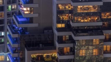 Modern kulelerin pencerelerinde ışık var. Geceleri parlayan pencereleri ve balkonları olan bir apartmanın dışında. Gökdelenin yukarıdan aydınlatmalı havadan görünüşü