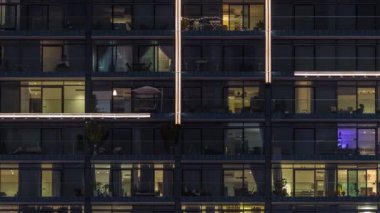 Çok katlı cam binaların panoramik pencerelerindeki çok renkli ışıkların düz gece panoraması. Büyük bir şehirde aydınlık bir gökdelen.
