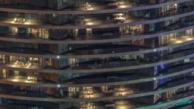 Gece vakti üst sınıf bir binanın pencerelerinin önünde oturuyorlardı. Gökdelende parlayan ışıklar. Balkonlarda sandalyeler