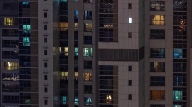 Gece karanlığında parlayan gökdelen dairesinin camları şehrin ışıklarını yansıtıyor. İş bölgesinde aydınlık kuleler