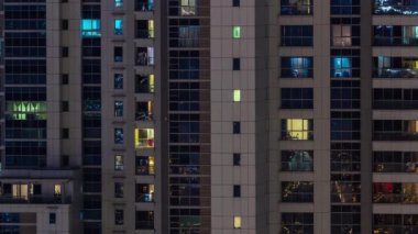 Gece karanlığında parlayan gökdelen dairesinin camları şehrin ışıklarını yansıtıyor. Balkonları olan aydınlık kuleler