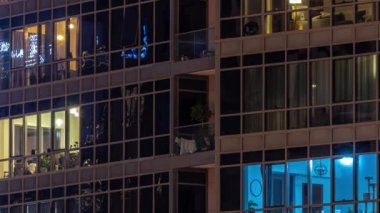 Modern şehir zaman diliminde geceleri gökdelenlerdeki ışık panoramik pencerelerle dolu. Parlak aydınlatma