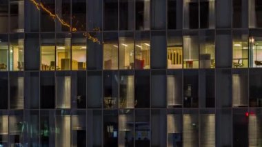 Aydınlatılmış çalışma odaları zaman ayarlı ofis cam pencere cephesinin gece görüşü. Gökdelende parlayan ve yanıp sönen ışık