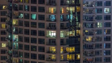 Dışarıdaki apartmanın akşam manzarası. Parlayan pencereleri olan bir bina. Işıklı gökdelenle aydınlatılmış yüksek bir gökdelen