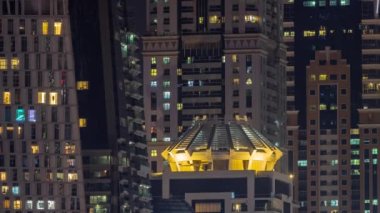 Parlak pencereli, dış apartman manzaralı bir zaman çizelgesi. Dubai marinasında ışıkları olan gökdelenler.