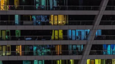 Apartman kulesindeki panoramik pencerelerin gece görüşü. Odalarında ışıklar olan yüksek gökdelenli