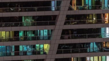 Apartman binasının parlayan pencerelerinin gece görüşü. Işıklı ve hareketli yüksek gökdelenler