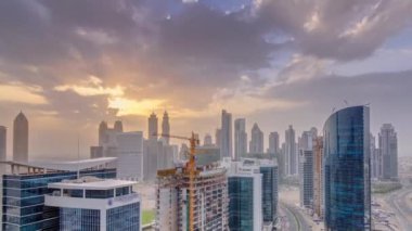 Dubai iş hangarı kuleleri, gün batımında hava zaman tüneli panoramasında. Bazı gökdelenlerin çatı manzarası ve inşaat halindeki yeni kuleler.