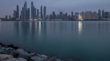 Gün geçiş timelapse Dubai şehir gece Palm Jumeirah Adası'içinde modern gökdelenler Panoraması. Dubai, Birleşik Arap Emirlikleri. Dubai Yat Limanı ve sabah erken bulutlara Jbr