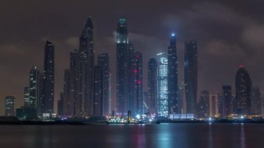 Gün geçiş timelapse Dubai şehir gece Palm Jumeirah Adası'içinde modern gökdelenler. Dubai, Birleşik Arap Emirlikleri. Dubai Yat Limanı ve sabah erken bulutlara Jbr