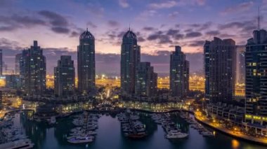Dubai Marina 'da gündoğumundan önce Dubai, BAE' de yatlarla modern gökdelenlerin gece gündüz hava panoramik görüntüsü. Sabahın erken saatlerinde aydınlık kuleler