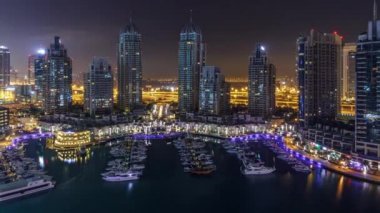 Dubai Yat Limanı bütün gece timelapse, Glittering ışıklar swithcing kapalı ve en yüksek gökdelenler sırasında. Işıklı kuleleri, yatlar ve arka plan üzerinde yolda trafik