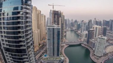 Dubai Marina gezinti güvertesi ve kanalı, gün batımından sonra Dubai, BAE 'de yüzen yat ve teknelerle panoramik hava manzaralı. Modern kuleler ve yoldaki trafik.
