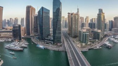 Dubai Marina gezinti güvertesi ve kanalı, gün batımından sonra Dubai, BAE 'de yüzen yat ve teknelerle panoramik hava manzaralı. Modern kuleler ve yoldaki trafik.