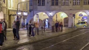 Prag 'daki tramvay durağında insanların olduğu ışıklı malostranske namesti meydanının gece görüşü. Aziz Nicolas Kilisesi 'yle ünlüdür. PRAG, ÇEK CUMHURİYETİ