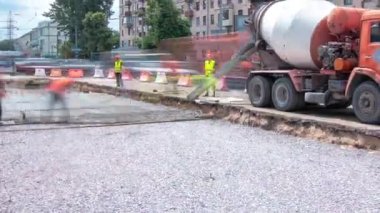 Tramvay rayları onarımı ve bakım zamanı olan bir yol inşaatı. Somut, kavşağın ortasında turuncu mikserle çalışıyor. Yeni toplu taşıma için demiryolu raylarının değiştirilmesi