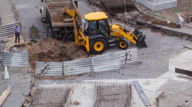 Tramvay rayları onarımı ve bakım havası olan bir yol inşaatı. Kazıcı bir çöp kamyonuna toprak yüklüyor. Kavşağın orta kısmında beton işe yarar..