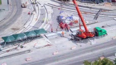 Tramvay rayları onarımı ve bakım havası olan bir yol inşaatı. Kavşağın ortasına vinçten kamyona beton plakalar yükleyip yüklüyorlar..