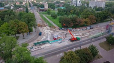 Tramvay rayları onarılan ve panoramik panoramik zaman ayarlı yol inşaatı. Kavşağın ortasında vinç üstüne beton plaka yükleme ve yükleme ve bloklar