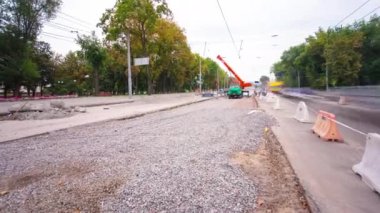 Tramvay rayları onarımı ve bakım zamanı olan bir yol inşaatı. Turuncu vinç sokağın ortasında çalışıyor. Yeni toplu taşıma için demiryolu raylarının değiştirilmesi