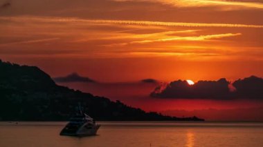 Güneş doğarken Beaulieu sur mer, Fransa 'dan deniz ve manzaranın yakın görüntüsü. Tekneler ve yatlar ön planda. Sudaki yansımalar.