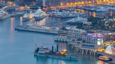 Monako 'nun büyük Corniche yolundan gece geçiş zamanına, yukarıdan Monako Fransa' ya olan hava manzarası. Akşam aydınlatması. Limanın suyundaki yansımalar