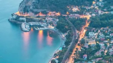 Günbegün Akdeniz kıyı şeridini teknelerle gösteren geçiş zamanı. Günbatımından sonra Fransız Rivierası 'ndaki Eze köyünün tepesinden ortaçağ evleri.