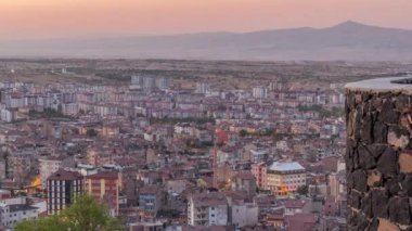Nevsehir 'in tarihi kentindeki eski şatonun hava görüntüsü. Gündüzden geceye geçiş zamanı. Gün batımından sonra aydınlatılmış binalar ve yollar ile panoramik gökyüzü
