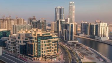 Gün batımında Bay Square bölgesinde karışık kullanım ve Dubai 'deki Business Bay' de bulunan düşük katlı kompleks ofis binaları. Yukarıdan hava manzaralı ve yolda trafik var.
