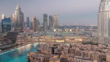 Dubai Uluslararası Finans Merkezi 'nin hava görüntüsü günden geceye geçiş zamanı. Şehir merkezinde modern gökdelenleri ve alışveriş merkezleri olan ofis kuleleri ve oteller