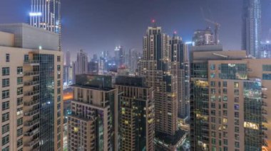 Dubai gökdelenleri tüm gece boyunca business bay bölgesinde aydınlatma ile. Birleşik Arap Emirlikleri 'nde şehir merkezindeki kulelerin tepesinden sisli hava manzarası. Işıklar kapanıyor.