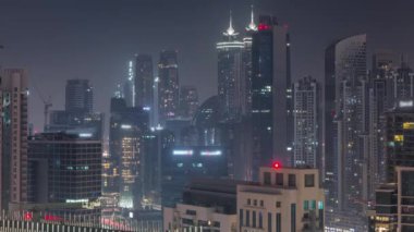 Dubai gökdelenleri tüm gece boyunca business bay bölgesinde aydınlatma ile. Birleşik Arap Emirlikleri 'nde şehir merkezinden sisli hava manzarası. Işıklar kapanıyor.