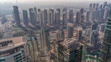 JLT ve Dubai Marina gökdelenleri Sheikh Zayed Yolu 'nun kesiştiği yerde. Yukarıdan hava manzaralı gölgeler hızla ilerliyor ve otoyolda trafik var.