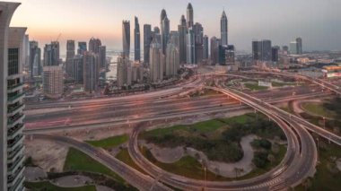 Dubai Marina karayolu kavşağındaki panorama spagetti kavşağı günden geceye geçiş zamanı. Arka planda en uzun gökdelenler aydınlatılıyor. Gün batımından sonra JLT bölgesinden hava görüntüsü